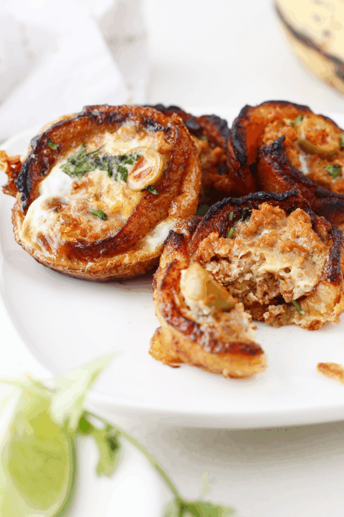 Plate of multiple plantain cups, one partially eaten to reveal the seasoned ground beef and olive filling.