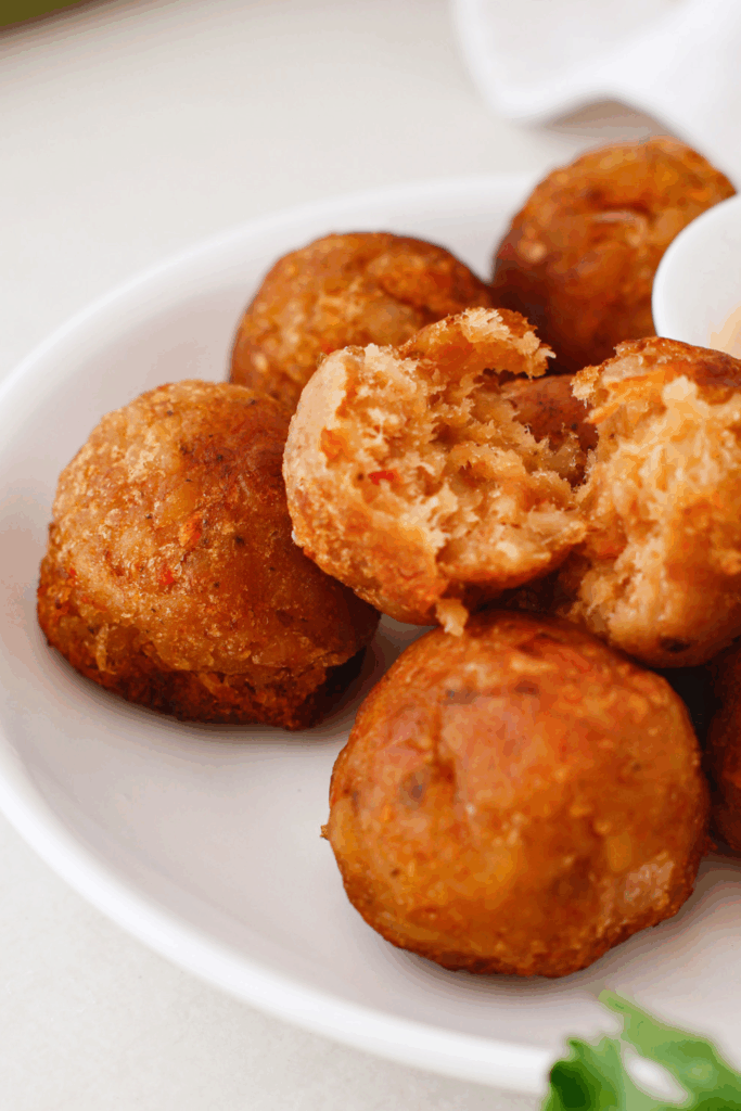 A mofongo ball split in half revealing a soft, seasoned mashed plantain interior with colorful bits of garlic and onion.