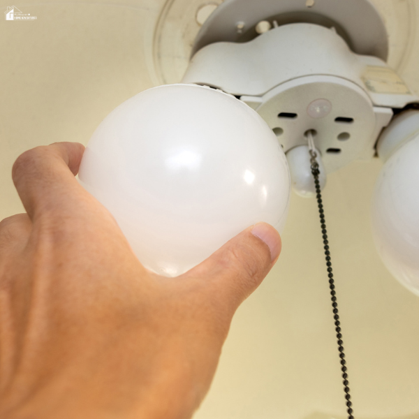 Close-up of a person installing a lightbulb in a ceiling fixture to brighten an apartment interior.