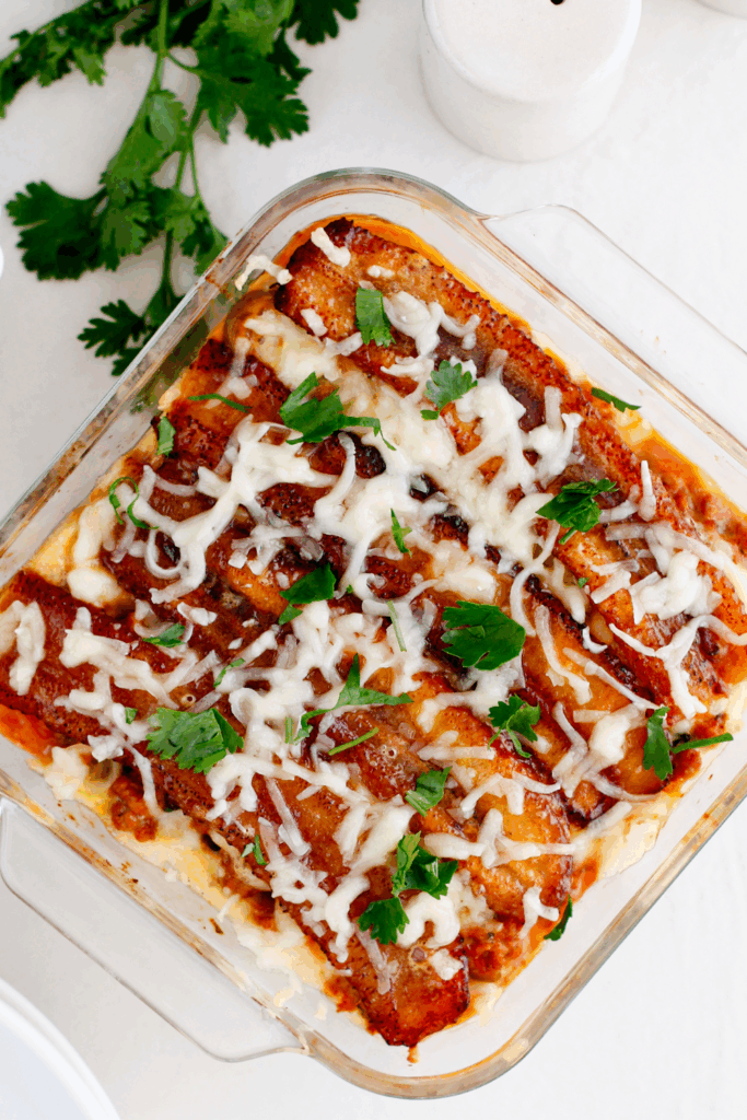 Puerto Rican pastelón topped with melted cheese and fresh parsley in a baking dish.