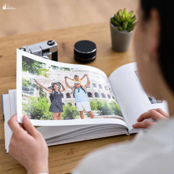 A woman flips through a photo book featuring a family posing in front of the Colosseum.
