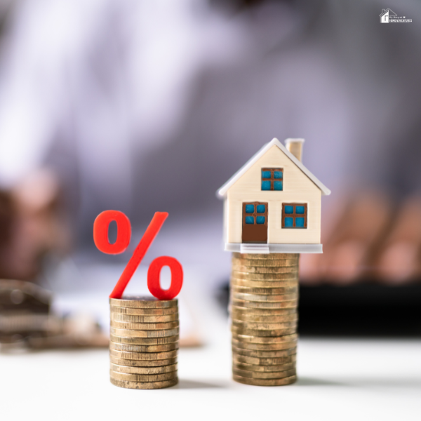 Stacked coins with a house and percentage sign represent budgeting strategies for home maintenance and energy savings.