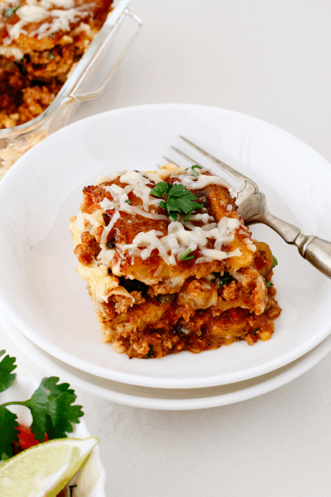 A single serving of pastelón on a plate, featuring rich layers of ground beef, cheese, and sweet plantains.