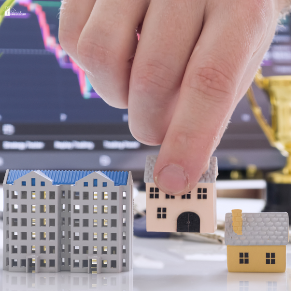 A hand selecting a model house from a group of properties, symbolizing how real estate management companies help long-distance landlords handle property decisions remotely.