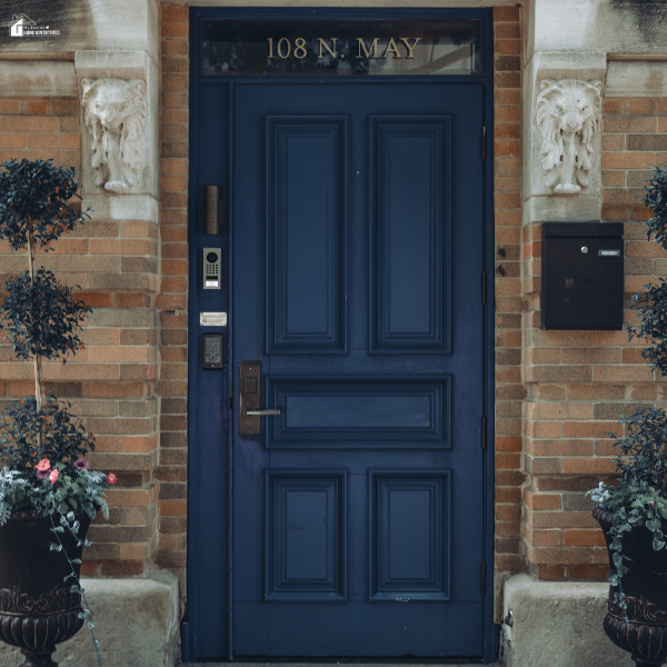 A modern dark blue front door with electronic security features installed on a brick house.