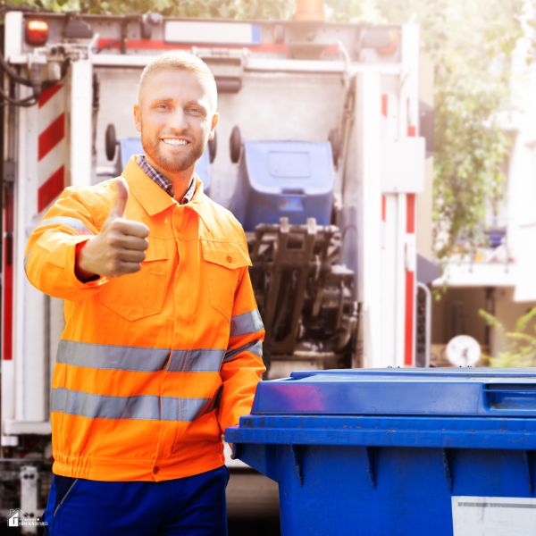 A smiling worker in safety gear gives a thumbs-up next to a bin, representing trusted garbage removal services.