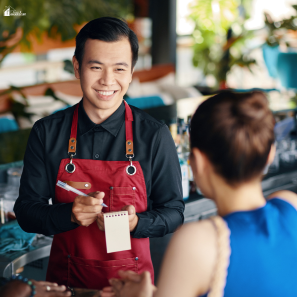 A restaurant server takes a customer’s order, highlighting the importance of efficient communication in high-volume restaurants using kitchen display systems.