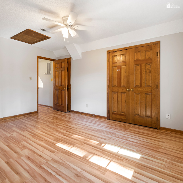 A bright bedroom with light wood flooring and natural light, showing an affordable and family-friendly flooring option.