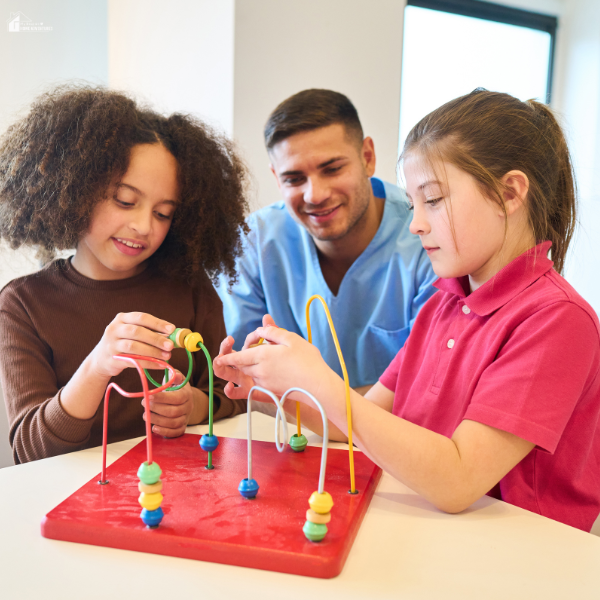 A child development specialist supports two children during a hands-on play therapy session, showcasing a lesser-known child development role.