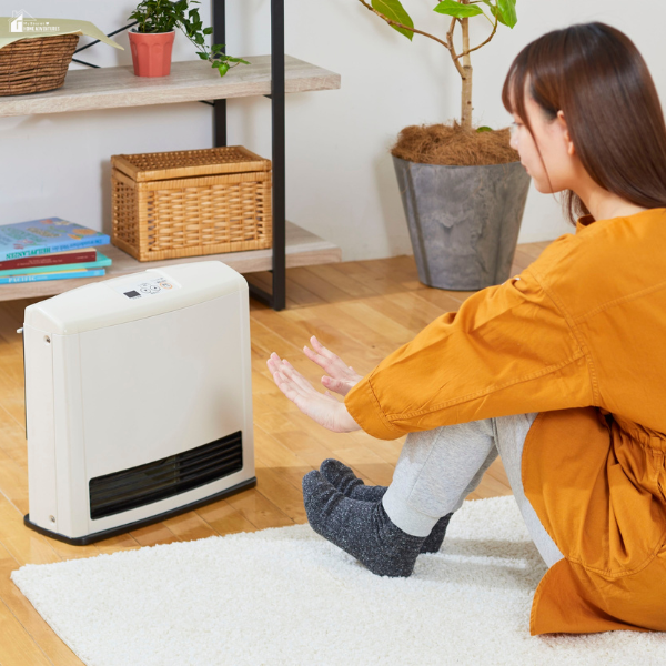 A guest sits comfortably by a space heater, showing how warmth is an essential feature that enhances comfort during a stay.