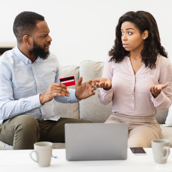 A couple reviews finances together on a couch, reflecting a supportive approach to resetting a budget after overspending without shame.