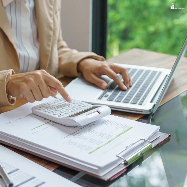 Hands calculate expenses beside financial paperwork and a laptop, showing practical steps to reset a budget after overspending.