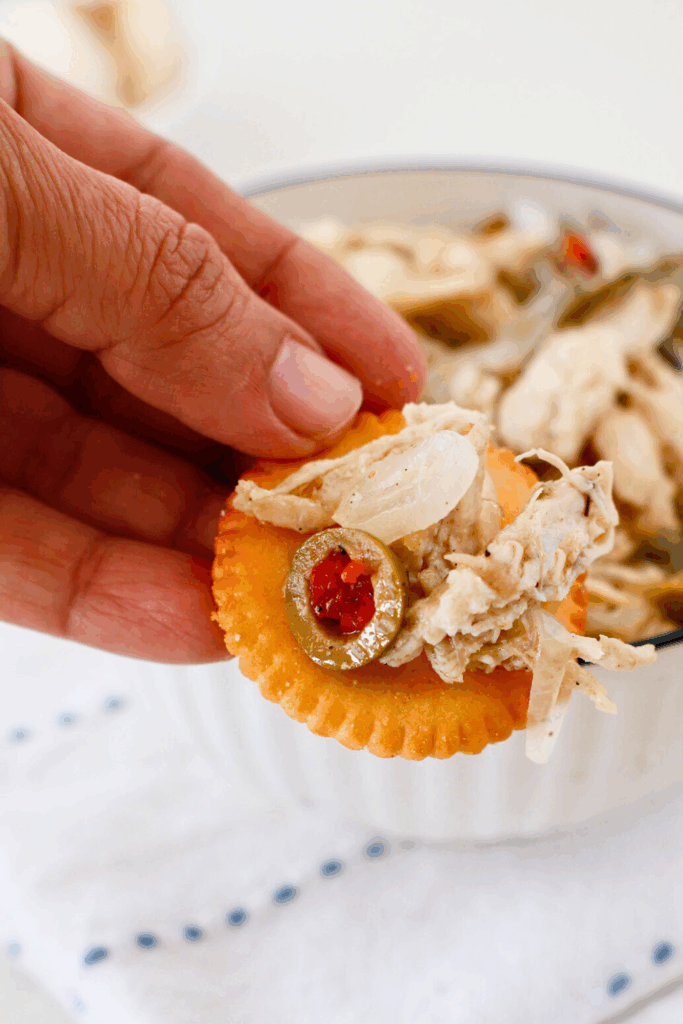 Pollo en escabeche served on a cracker with vinegar marinated chicken, onions, and green olives, a classic Puerto Rican chicken dish often enjoyed as an appetizer or party food