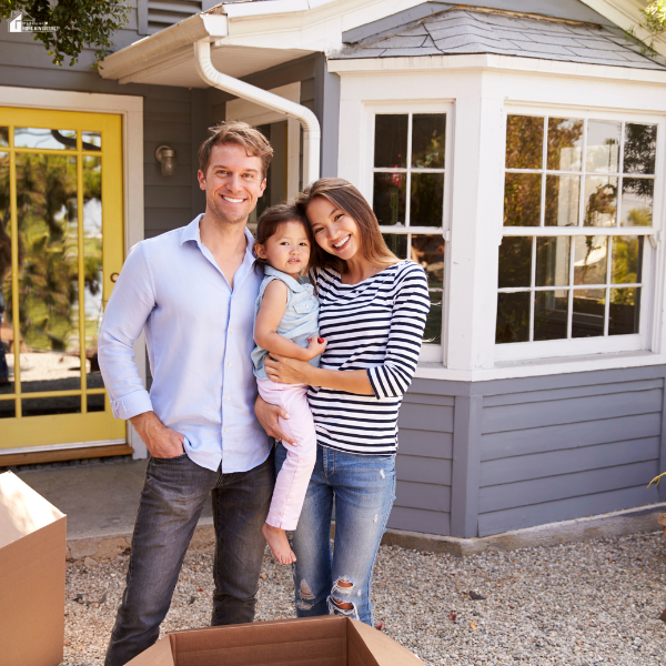 A young family stands outside a new house, representing a key moment in evaluating a potential family home before committing.