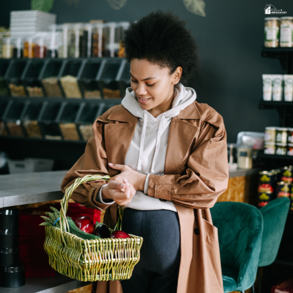 A pregnant woman shops locally, reflecting the importance of nearby amenities when assessing a home for long-term family needs.