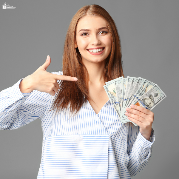 A woman smiling and pointing at money in her hand, representing simple ways to earn extra cash while living on a fixed income.