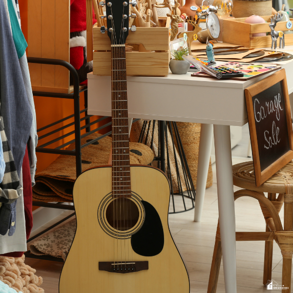 An acoustic guitar displayed beside household items, representing valuable personal belongings that can be exchanged for fast money.
