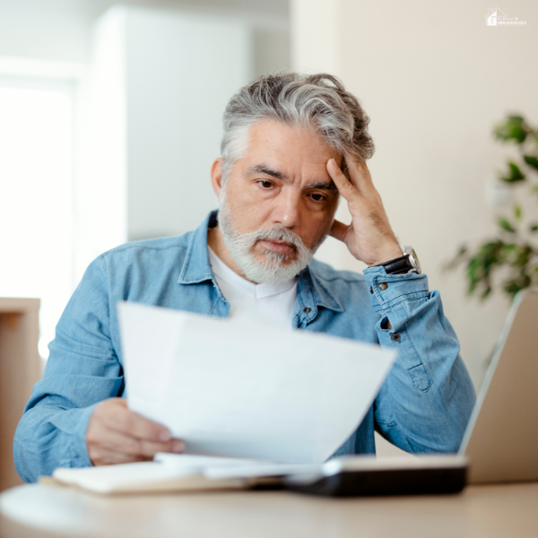A worried man reviewing high energy bills, possibly due to a faulty split system that's showing signs of trouble.