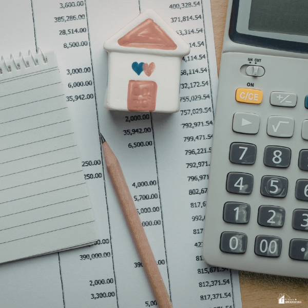 A calculator, notebook, pencil, and home figurine rest on financial paperwork, illustrating everyday household expenses that slowly add up over time.