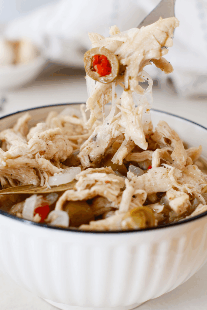 Shredded pollo en escabeche with vinegar marinated chicken, onions, olives, and spices served in a bowl, a classic Puerto Rican chicken recipe made ahead for family meals and gatherings