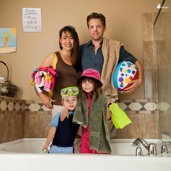 Family standing in a bathroom with towels, pool toys, and swim gear to represent turning everyday spaces into fun staycation experiences at home.