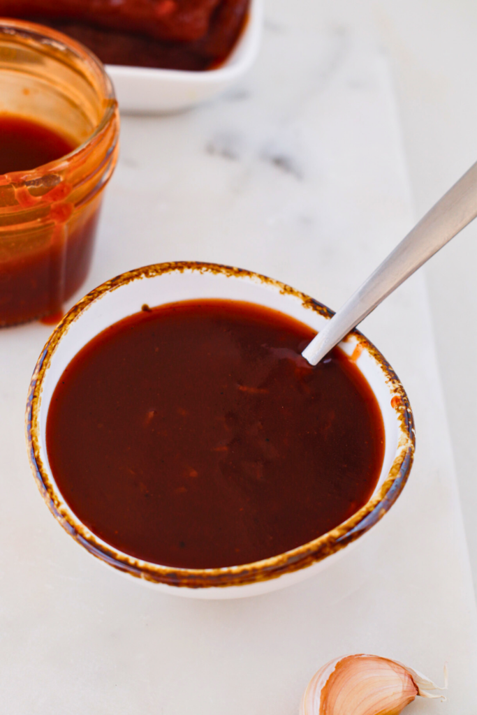 Puerto Rican guava BBQ sauce in a white bowl with spoon, smooth sweet and tangy Caribbean barbecue sauce made with guava paste, perfect for grilled chicken, pork, and ribs