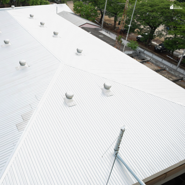 A large white metal commercial roof with ventilation units installed, showcasing durable roofing materials designed for long-term building protection.