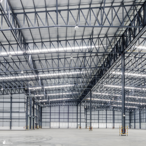Interior view of a spacious industrial warehouse with exposed steel beams and metal roofing structure, emphasizing strength and structural performance.