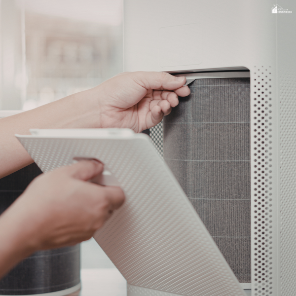 Hands removing a dirty air filter from a home ventilation system to improve indoor air quality.
