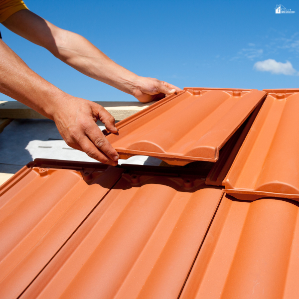 Close-up of a roofer installing interlocking metal roof panels, highlighting durable roofing materials that help reduce repair costs and improve long-term home protection.