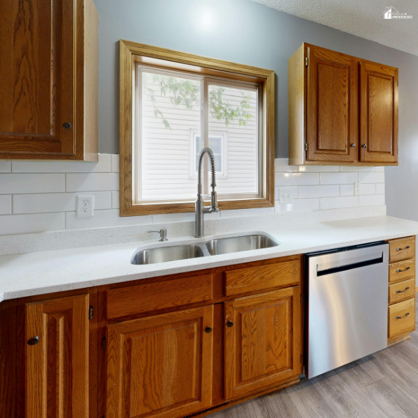Kitchen with warm wood cabinets, white backsplash, and ample counter space highlighting storage and functional layout choices.
