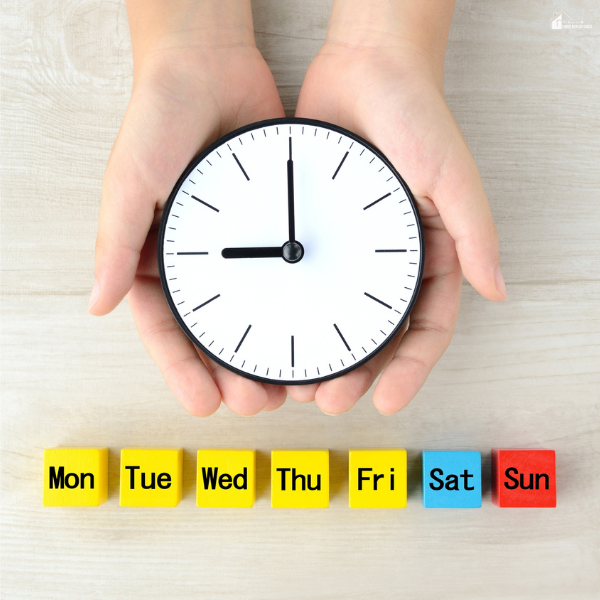 Hands holding a clock above weekday markers to represent planning a structured weekly routine that protects mental energy.