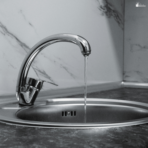 Kitchen sink faucet dripping water into a basin, representing a common household issue that signals potential plumbing trouble.