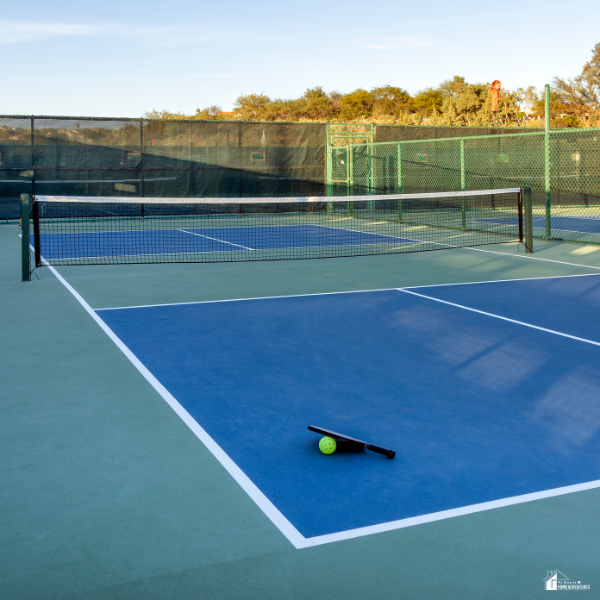 A paddle and ball rest on a backyard pickleball court, representing an easy way to turn your yard into an activity space.