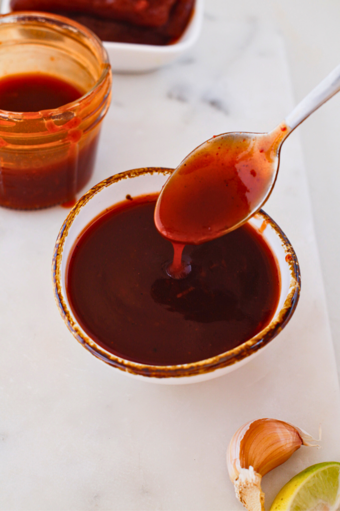 Puerto Rican guava BBQ sauce in a bowl with spoon, thick sweet and tangy homemade Caribbean barbecue sauce made with guava paste, perfect glaze for grilled chicken, pork, ribs, and pinchos