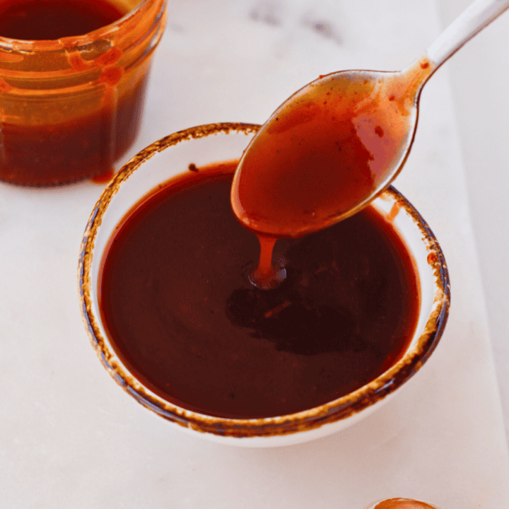 Puerto Rican guava BBQ sauce in a bowl with spoon, thick sweet and tangy homemade Caribbean barbecue sauce made with guava paste, perfect glaze for grilled chicken, pork, ribs, and pinchos
