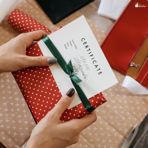 A person presents a wrapped gift with a certificate, representing the growing trend of giving experience-based gifts instead of physical items.