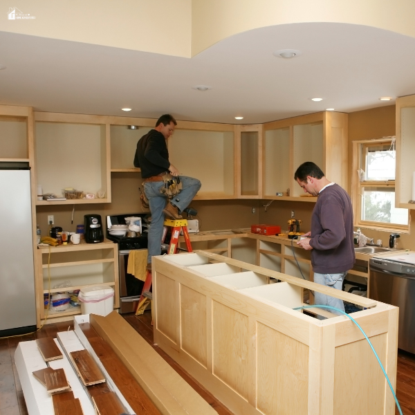 Contractors installing cabinets in a kitchen renovation, illustrating cost-conscious upgrades that balance quality and affordability.
