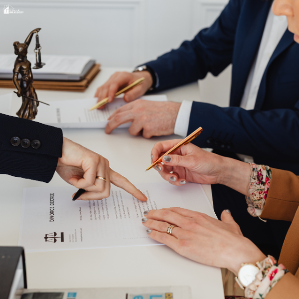 Two individuals reviewing legal paperwork with a lawyer while discussing financial matters during a marital separation.