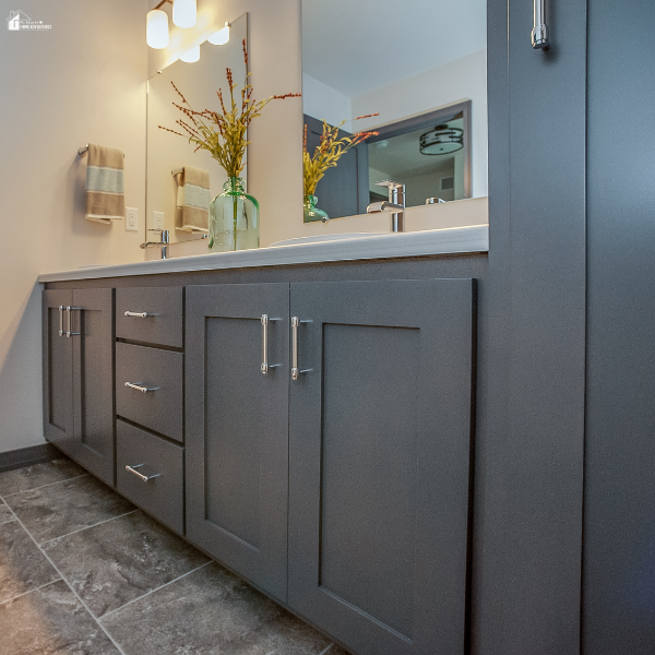 Modern bathroom vanity with gray cabinets, sleek hardware, bright lighting, and a large mirror creating a clean and updated bathroom space.