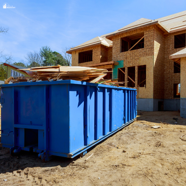 Temporary dumpster filled with wood scraps and building materials at a residential construction site during final cleanup.