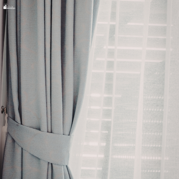 Sheer and blackout curtains layered together on a window, showing soft light filtering and privacy control in a styled space.
