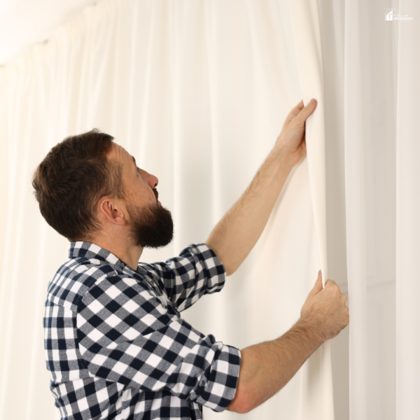 Person adjusting layered curtains to balance natural light and privacy using sheer and blackout panels.