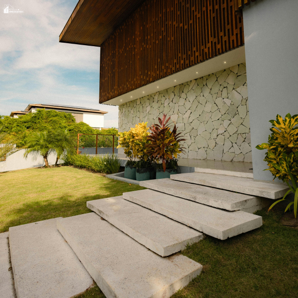 Modern home exterior with stone wall accents, landscaped yard, and concrete steps showing curb appeal upgrades that increase property value.
