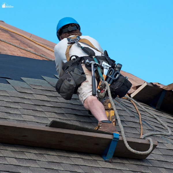Professional roofer wearing safety gear working on a residential roof during a roofing repair or installation project.