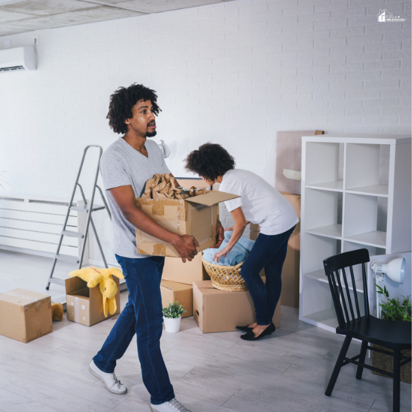 Couple packing boxes while clearing a room, representing the moving process and preparing a home for move-out cleaning.