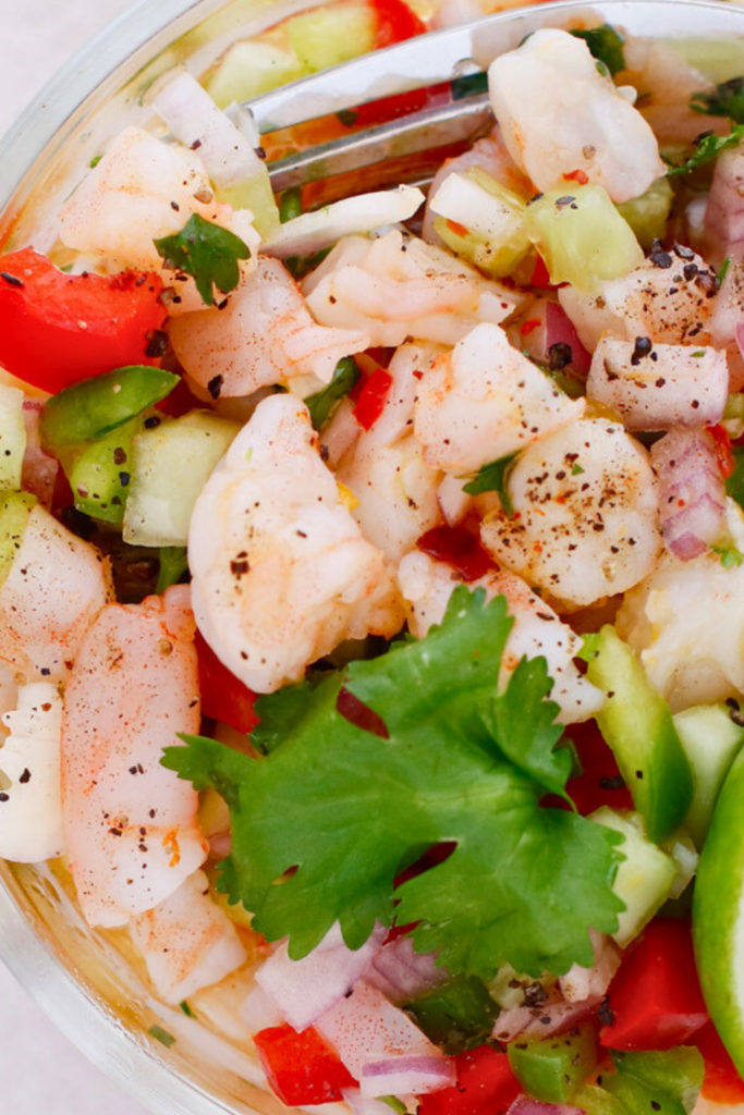 Puerto Rican shrimp escabeche close up with citrus marinade, fresh vegetables, cilantro, and peppers, a cold shrimp recipe with lime, onion, and cucumber