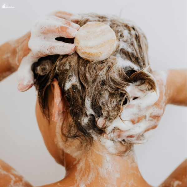 Person washing their hair with a shampoo bar during an affordable at-home self-care routine that helps busy moms relax without spending much.