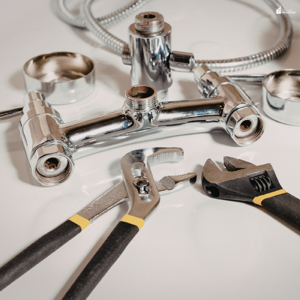 Plumbing tools and fittings arranged on a surface, representing essential equipment for seasonal plumbing maintenance in a home.