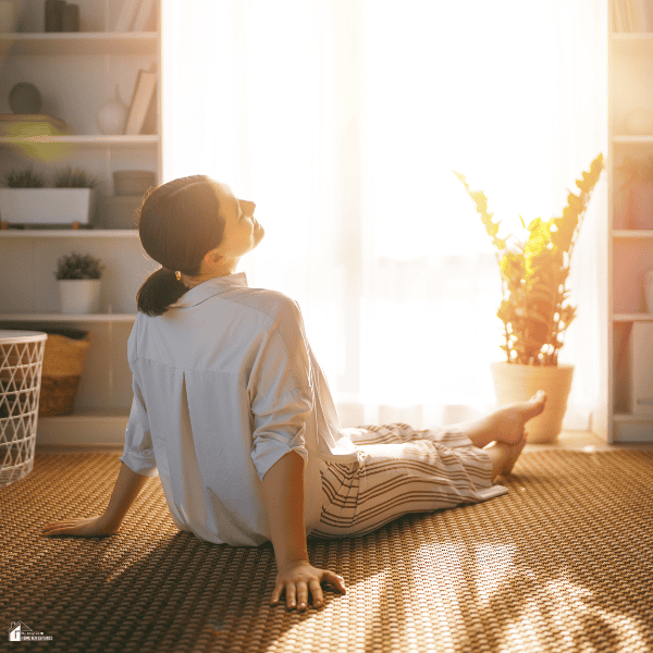 Person relaxing on the floor in a bright, tidy room, showing how small DIY fixes can create a calm and comfortable living space.